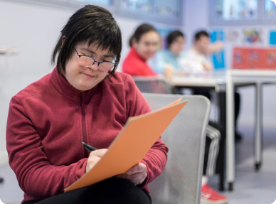 Joven estudiante concentrado en leer material educativo, una imagen que refleja el enfoque en la información institucional.