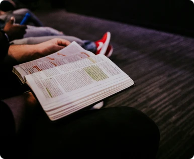 Persona sentada leyendo y subrayando un libro atentamente
