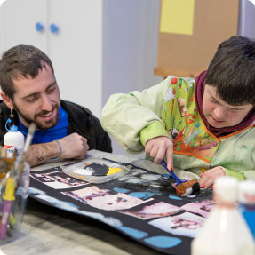 Profesor asistiendo a un joven en una actividad de pintura en el centro Río Irati.